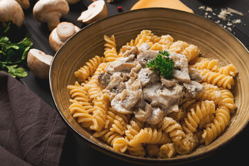 Fusilli pasta, with champignons in cream sauce, top view, with ingredients, on a wooden table, no people,