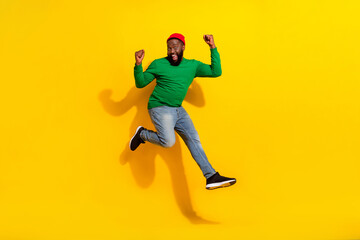 Fototapeta na wymiar Photo of crazy nice confident guy jump rejoice success wear red beanie green shirt isolated yellow color background