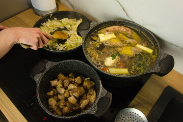 Woman cooking traditional Sunday dinner on electric induction hob