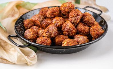 Baked meat ball on rustic black pan, scarf on white background.