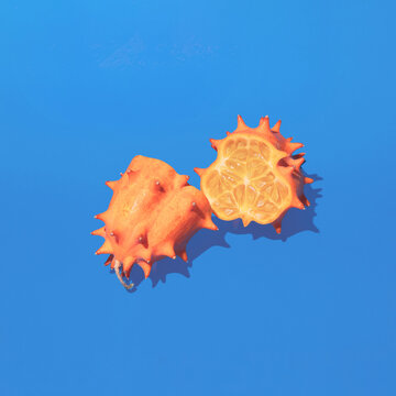 Kiwano cut in half against pastel blue background. Minimal square composition, healthy nutrition detox fruits concept