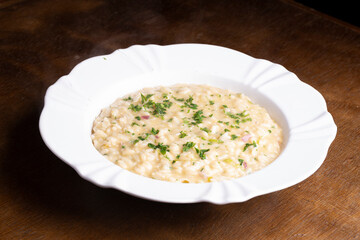 plate of risotto with green onions on wooden table
