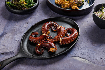 A portion of risotto with octopus tentacles. purple background. Top view