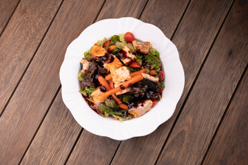 salad plate with vegetables and grilled salmon on wooden table top view