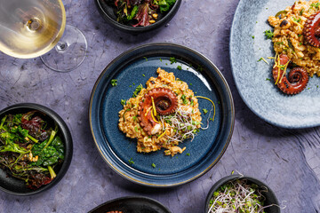A portion of risotto with octopus tentacles. purple background. Top view