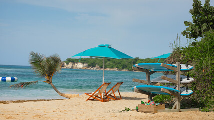 Fototapeta na wymiar Surfboards, sun loungers on ocean beach, relaxation area