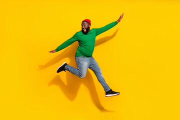 Fototapeta na wymiar Photo of carefree inspired cheerful guy jump plane pose wear red beanie green shirt isolated yellow color background