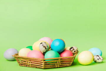 Multi colors Easter eggs in the woven basket on colored background . Pastel color Easter eggs. holiday concept with copy space