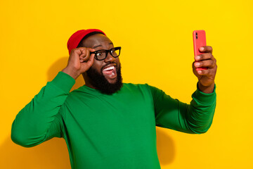 Portrait of handsome trendy cheerful guy using device fast 5g touching specs taking selfie isolated on vivid yellow color background