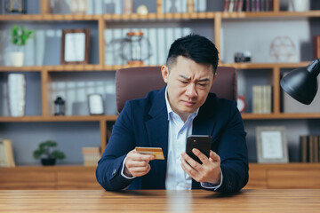Upset man trying to make a purchase in an online store, Asian businessman working in a classic...