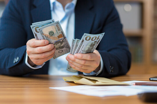 Close-up photo of businessman's hands counting cash US dollars, man working in office