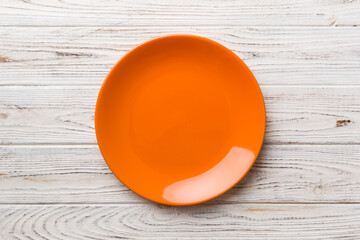 Top view of empty orange plate on wooden background. Empty space for your design
