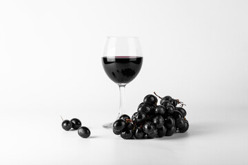 Red wine in glasses with grapes on white background.