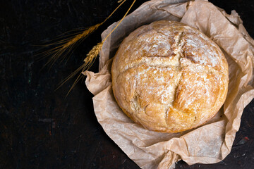Fresh homemade crisp bread on Kraft paper with rye sticks over black table. Healthy baked bread on...