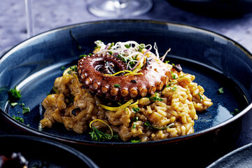 A portion of risotto with octopus tentacles. purple background. Top view