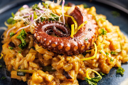 A portion of risotto with octopus tentacles. purple background. Top view