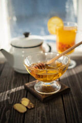 jar of honey and hot drink with sea buckthorn berry, ginger, lemon against the background of the window
