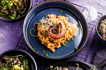 A portion of risotto with octopus tentacles. purple background. Top view