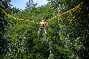 The boy is jumping on a bungee trampoline. A child with insurance and stretchable rubber bands...