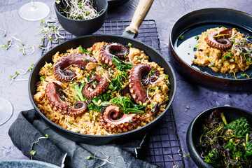 A portion of risotto with octopus tentacles. purple background. Top view