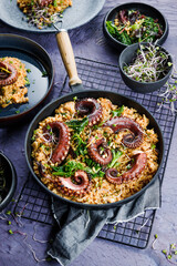 A portion of risotto with octopus tentacles. purple background. Top view © karepa