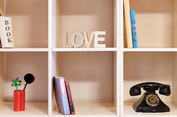 shelf with books old phone and letters with the word love