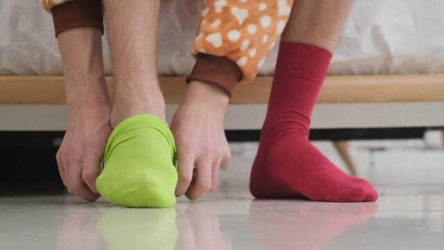 A unique man puts socks of different colors on his feet