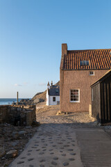 Obraz premium 20 March 2022. Crovie, Aberdeenshire, Scotland. This is the row of houses that was the old coastal fishing village of Crove carching the Sun. The ver small village is now mostly holiday homes.