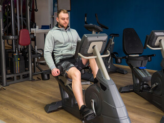 Fototapeta na wymiar guy on an exercise bike in the gym. Fitness, workout and healthy lifestyle