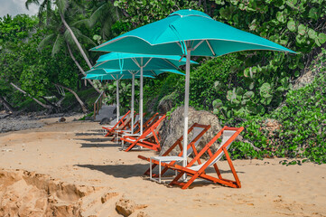 Sun loungers and umbrella on white sandy beach. Relax zone