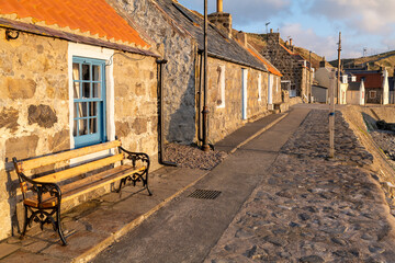 Fototapeta na wymiar 20 March 2022. Crovie, Aberdeenshire, Scotland. This is the row of houses that was the old coastal fishing village of Crove carching the Sun. The ver small village is now mostly holiday homes.