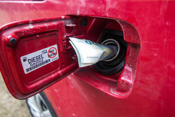 Fototapeta premium Banknotes, euro in the fuel filler of a red car.