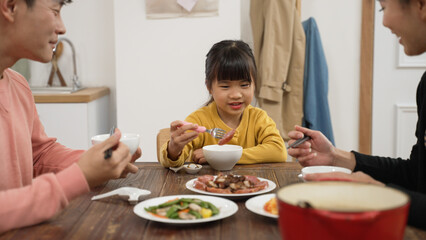 selective focus of picky Asian little girl eat the meat whit the fork at dining table home