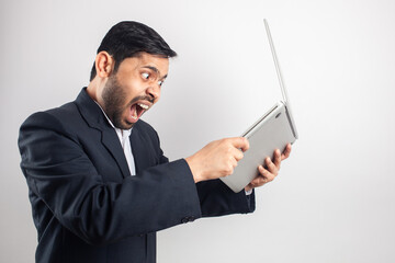 young indian angry businessman breaking laptop, hate technology