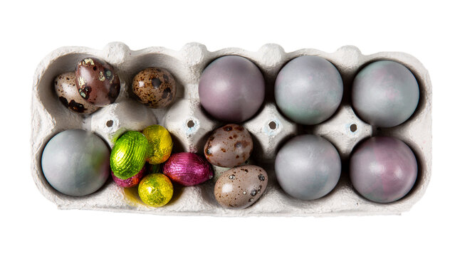 Colorful Easter eggs and chocolate eggs in cardboard packaging isolated on white. Top view.