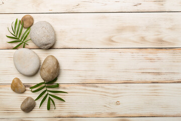 Spa stones and leaves on wooden background, top view