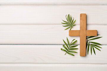 Palm branches and cross on wooden background, top view. Palm Sunday concept