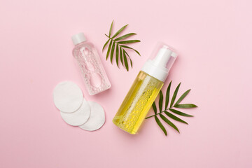 Foaming facial cleanser and micellar water on color background, top view