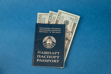 Belarusian passport with dollars on a blue background. Travel, vacation and emigration concept.