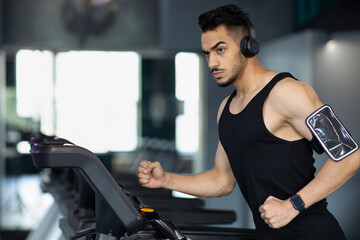 Fototapeta na wymiar Portrait Of Confident Muscular Arab Man Training On Treadmill At Modern Gym