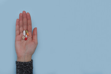 Woman hand with pills on palm. 
Colorful pharmaceutical medicine pills, narcotic drugs and vitamin in capsules on palm. Many different medications. Copy space for text.  - obrazy, fototapety, plakaty