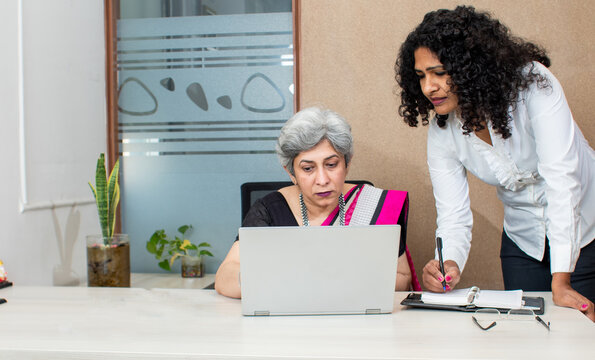 Two women in office looking at laptop and discussion project