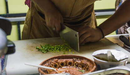 Mexican taquero at his typical stand preparing the meat and tortillas for tacos, putting some to go in their wrapper.