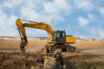 A working excavator with attachments on the construction of a road junction.