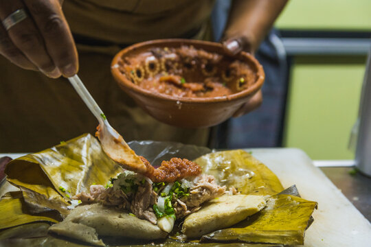Typical Mexican street food vendor, prepares a dish originally from Michoacan, Mexico called Corundas, among its ingredients is corn dough, pork, cream and hot sauce.