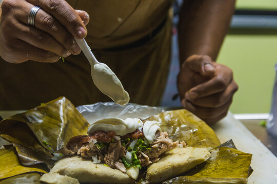 Typical Mexican street food vendor, prepares a dish originally from Michoacan, Mexico called Corundas, among its ingredients is corn dough, pork, cream and hot sauce.
