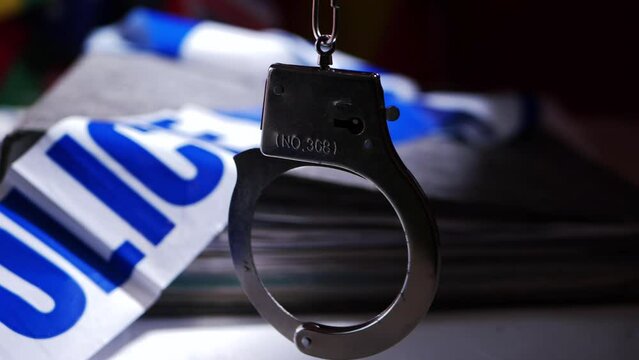 Handcuffs swinging with police files background