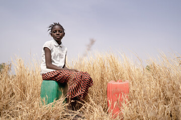 Black African Girl sad because she has to work hard in the fields instead of going to school. Child...