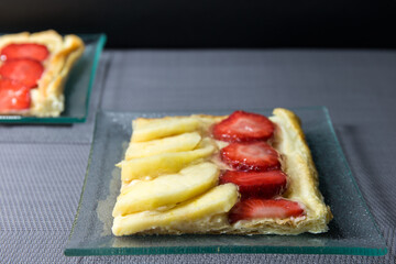 Portion of puff pastry with apple and strawberries served on a glass plate