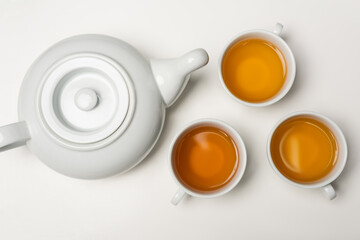 Obraz na płótnie Canvas Top view of cups of tea near teapot on white background.